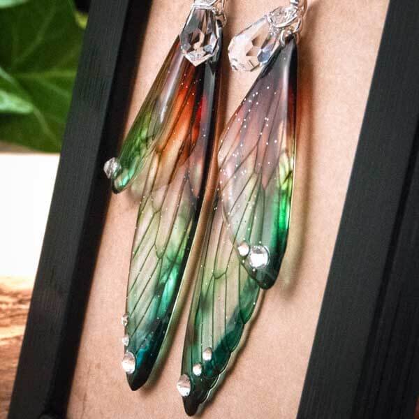 Gros plan des boucles artisanales longues en ailes de fée, couleur Perroquet (vert et orangé tropical)