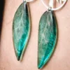 Gros plan des boucles d’oreille arbre de vie et ailes de fée turquoise