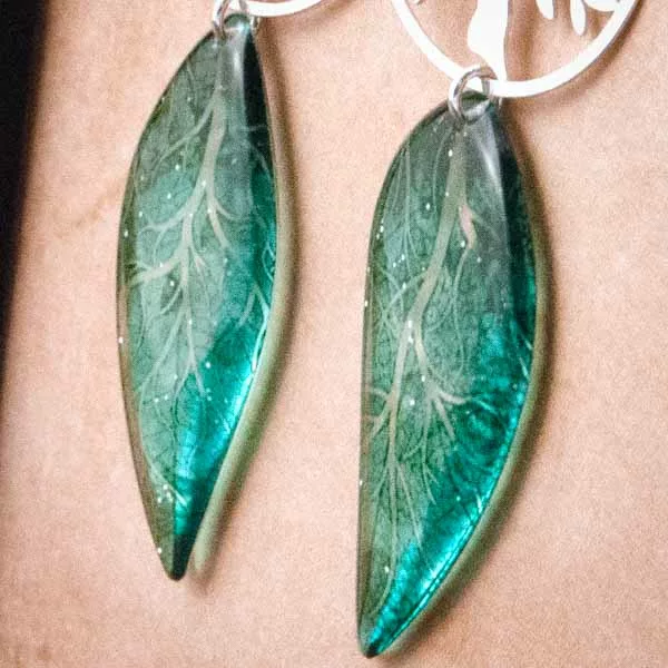 Gros plan des boucles d’oreille arbre de vie et ailes de fée turquoise