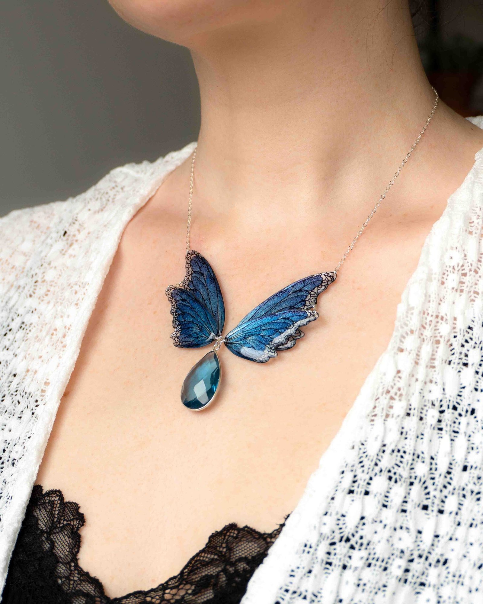 Collier Lioraëlys porté autour du cou, ailes de fée bleues en résine