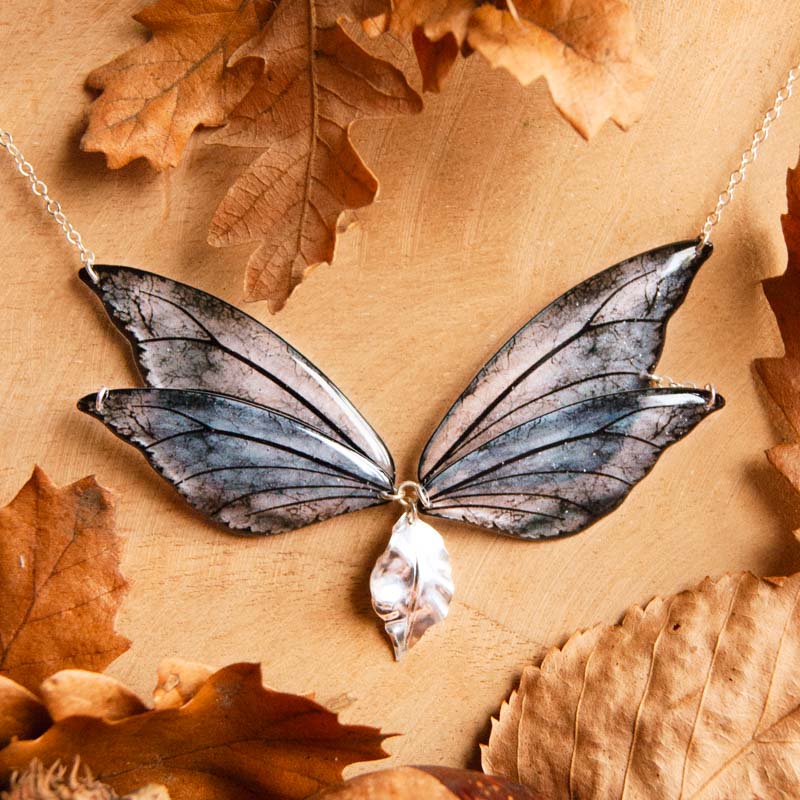 Collier créateur en ailes de fée Sylmeria – variante Tempête posé sur fond naturel