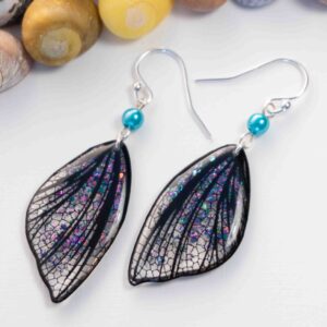 Boucles d’oreilles féeriques Eowyn aux ailes blanches et noires avec paillettes roses, violettes et turquoise
