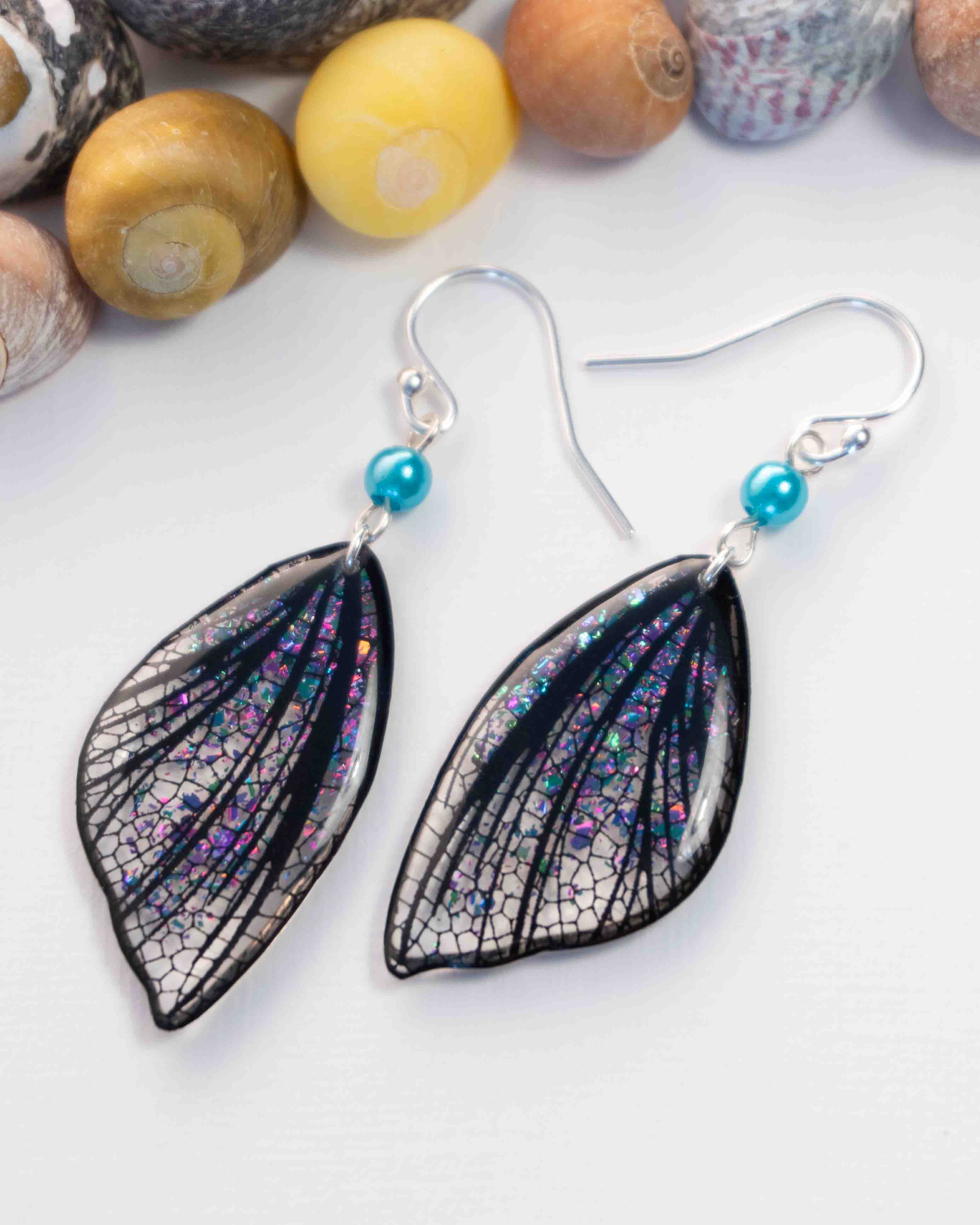 Boucles d’oreilles féeriques Eowyn aux ailes blanches et noires avec paillettes roses, violettes et turquoise