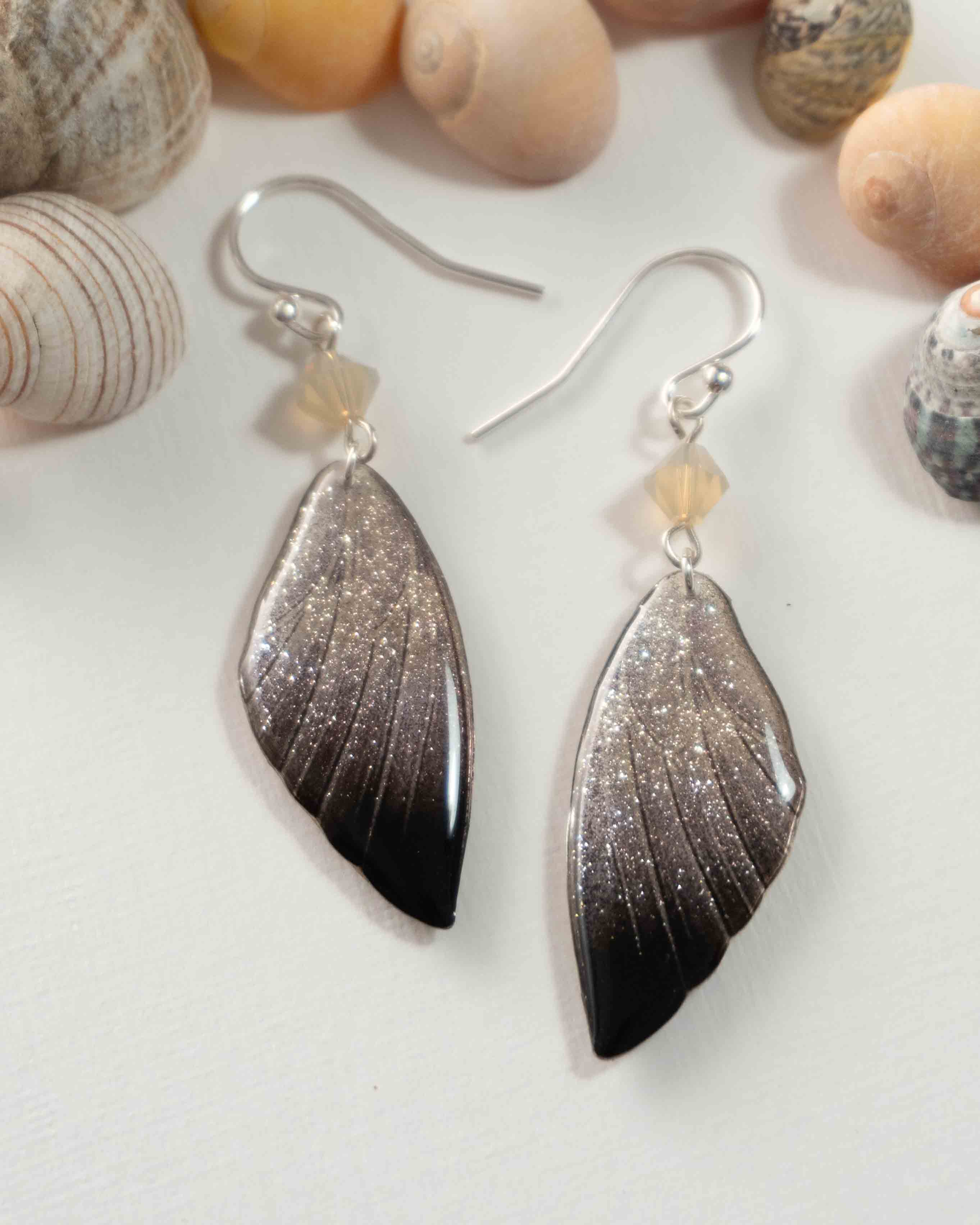 Boucles d’oreilles féeriques très scintillantes aux ailes argentées et noires