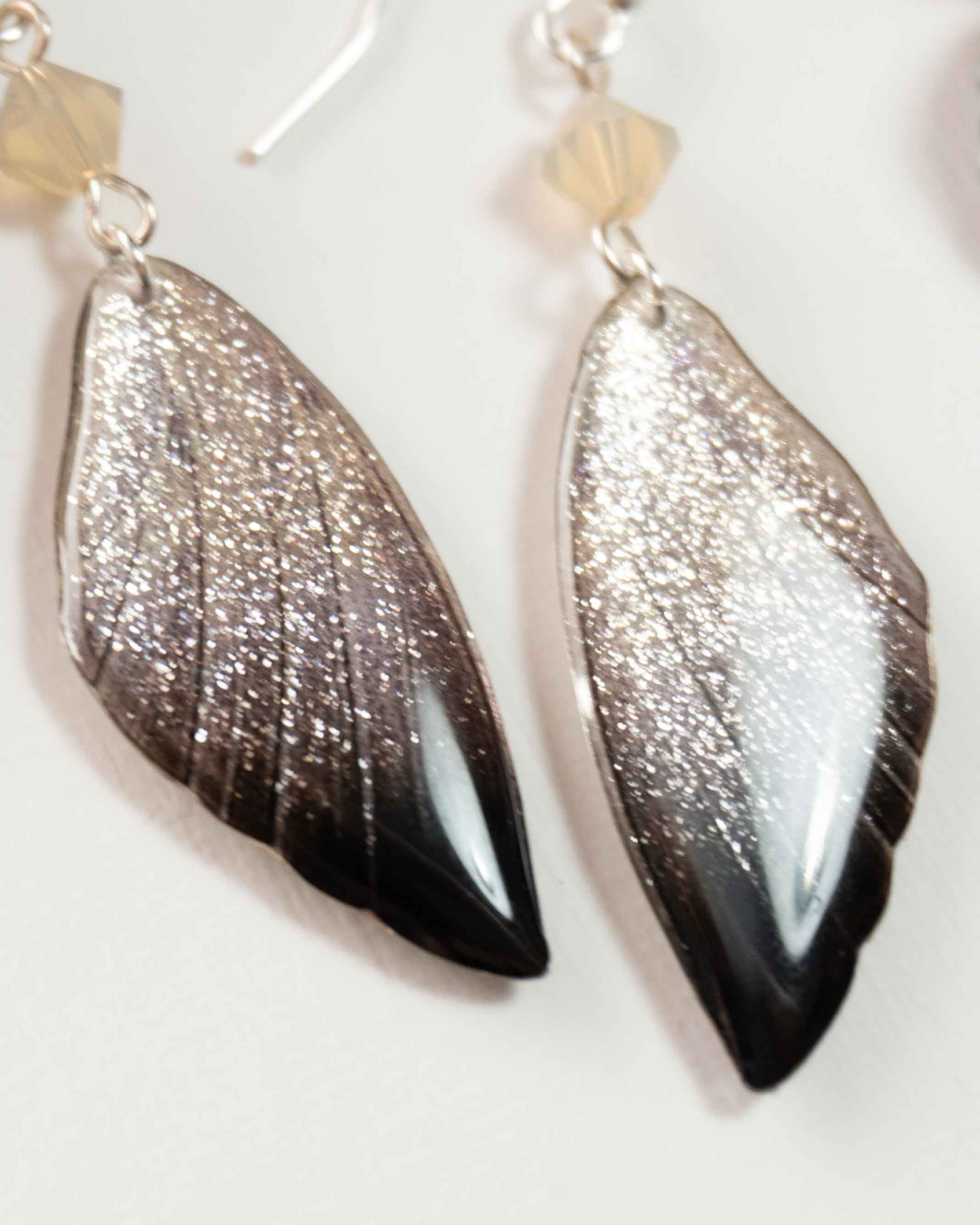 Boucles d’oreilles féeriques très scintillantes aux ailes argentées et noires