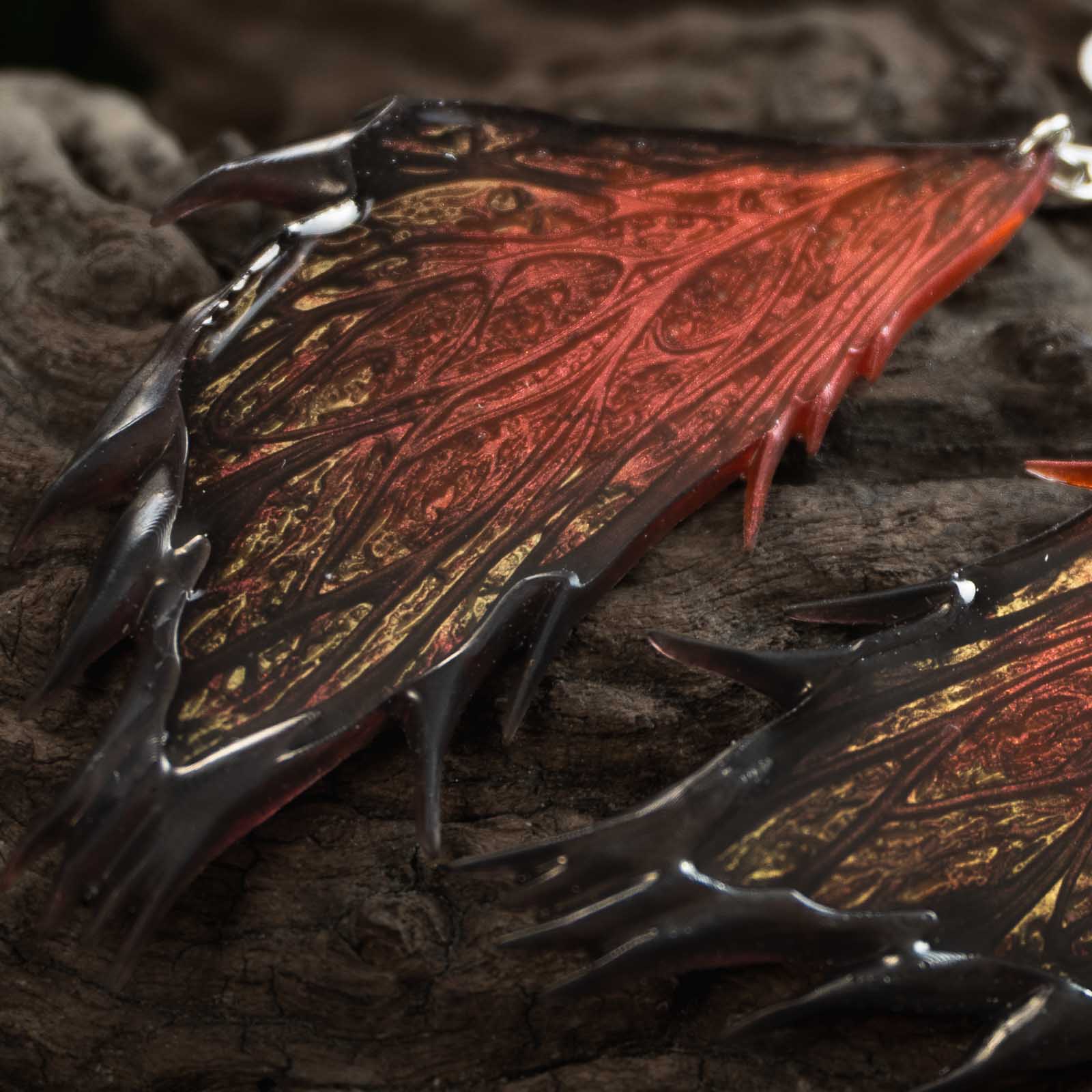 Gros plan sur les ailes des boucles d'oreilles Morgane Prestige, avec leurs nervures finement sculptées, leurs reflets or et leurs bordures noires pointues.