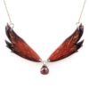 Collier Morgane Élégance composé de deux ailes de fée effilées aux nuances rouge cuivré, noir et or, ornées d'une perle de grenat.